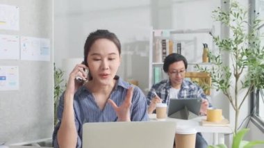 İki genç Asyalı girişim ortağı gündelik bir küçük işletme ofisinde çalışmaya, müşterilerle cep telefonuyla konuşmaya, dizüstü bilgisayarlı internet servis işleri ve E-ticaret KOBİ iş arkadaşı.