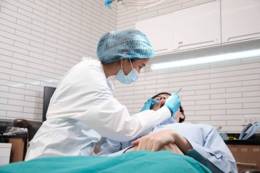 Asyalı kadın diş hekimi genç erkek dişlerini ve diş ağrısı stomatolojisini diş kliniğinde, sağlık kontrollerinde ve doktor muayenehanesinde profesyonel ortodontik sağlık hizmetlerinde inceleyecek..