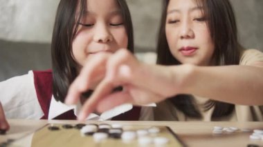 Yakın çekim, Asyalı aile zamanları, anne ve çocuk oyun oynuyorlar Go, dama masasında masa başında oyun oynuyorlar sevgi ve neşe dolu, çocuk ve ebeveynin rahatlatıcı hafta sonu hobileriyle..