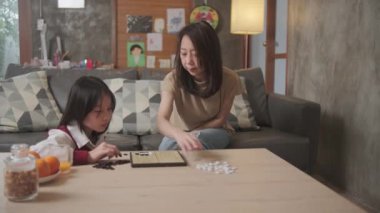 Asyalı aile, anne ve çocuk oyun oynuyorlar Go, dama masasında oyun oynuyorlar sevgi ve neşe dolu, çocuk ve ebeveynin rahatlatıcı hobisi, konsantre olup rekabet ediyorlar..