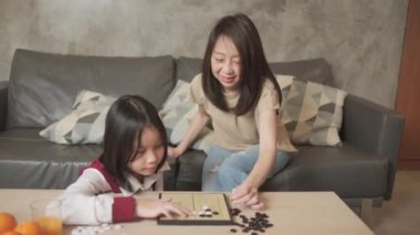 Asyalı aile, anne ve çocuk oyun oynuyorlar Go, dama masasında oyun oynuyorlar sevgi ve neşe dolu, çocuk ve ebeveynin rahatlatıcı hobisi, konsantre olup rekabet ediyorlar..