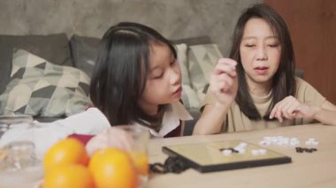 Asyalı aile, anne ve çocuk oyun oynuyorlar Go, dama masasında oyun oynuyorlar sevgi ve neşe dolu, çocuk ve ebeveynin rahatlatıcı hobisi, konsantre olup rekabet ediyorlar..