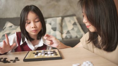 Asyalı aile, anne ve çocuk oyun oynuyorlar Go, dama masasında oyun oynuyorlar sevgi ve neşe dolu, çocuk ve ebeveynin rahatlatıcı hobisi, konsantre olup rekabet ediyorlar..
