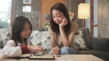 Asyalı aile, anne ve çocuk oyun oynuyorlar Go, dama masasında oyun oynuyorlar sevgi ve neşe dolu, çocuk ve ebeveynin rahatlatıcı hobisi, konsantre olup rekabet ediyorlar..