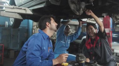 Profesyonel işçi ekipleri, çok ırklı mühendisler ve makine işçileri, garaj istasyonunda birlikte araba süspansiyonlarını tamir etmek ve sürdürmek ve otomotiv sektöründe hizmet işleri yapmak için işbirliği yapıyorlar..