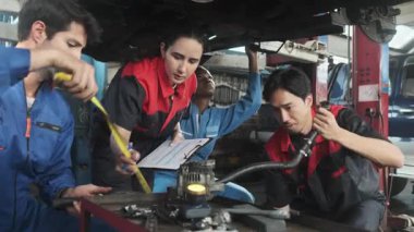 Profesyonel işçi ekipleri, çok ırklı mühendisler ve makine işçileri, garaj istasyonunda birlikte araba süspansiyonlarını tamir etmek ve sürdürmek ve otomotiv sektöründe hizmet işleri yapmak için işbirliği yapıyorlar..