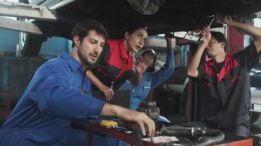 Profesyonel işçi ekipleri, çok ırklı mühendisler ve makine işçileri, garaj istasyonunda birlikte araba süspansiyonlarını tamir etmek ve sürdürmek ve otomotiv sektöründe hizmet işleri yapmak için işbirliği yapıyorlar..