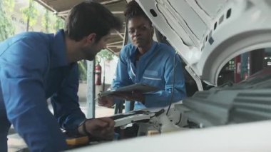 EV araba kontrolü, tamirci iş arkadaşı sabit otomobil garaj istasyonunda elektrik motoru ve pil hizmetini denetliyor ve koruyor, profesyonel teknoloji ulaşım sektörü.