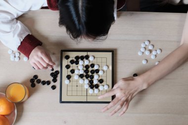 GO 'nun yakın çekim ve üst görüntüsü, tahta masa üzerinde oryantal dama tahtası oyunu iki Asyalı oyuncu, boş zaman hobisi, strateji kararı ve rekabetle ilgili taktik meydan okuma tarafından oynanır..