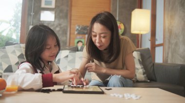 Asyalı aile, anne ve çocuk oyun oynuyorlar Go, dama masasında oyun oynuyorlar sevgi ve neşe dolu, çocuk ve ebeveynin rahatlatıcı hobisi, konsantre olup rekabet ediyorlar..