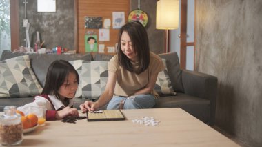 Asyalı aile, anne ve çocuk oyun oynuyorlar Go, dama masasında oyun oynuyorlar sevgi ve neşe dolu, çocuk ve ebeveynin rahatlatıcı hobisi, konsantre olup rekabet ediyorlar..