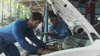 EV araba kontrolü, tamirci iş arkadaşı sabit otomobil garaj istasyonunda elektrik motoru ve pil hizmetini denetliyor ve koruyor, profesyonel teknoloji ulaşım sektörü.