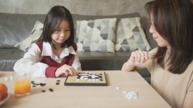 Asyalı aile, anne ve çocuk oyun oynuyorlar Go, dama masasında oyun oynuyorlar sevgi ve neşe dolu, çocuk ve ebeveynin rahatlatıcı hobisi, konsantre olup rekabet ediyorlar..