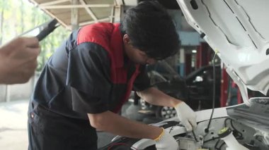 EV araba kontrolü, Asyalı erkek tamirci sabit otomobil garaj istasyonunda elektrik motoru ve pil hizmetini denetliyor ve koruyor, profesyonel teknoloji ulaşım sektörü.