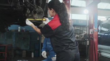 İki kadın tamirci tartışıyor, Latin ve Siyah işçiler otomotiv tekerleklerini tamir ediyor ve garaj istasyonunda araba süspansiyonlarını koruyor, ve araç taşımacılığı sektöründe teknisyen mühendisliği hizmeti veriyor.