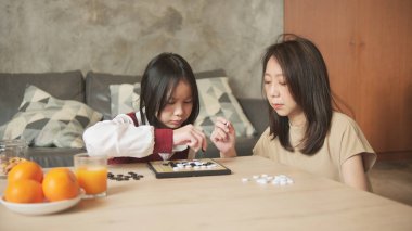 Asyalı aile, anne ve çocuk oyun oynuyorlar Go, dama masasında oyun oynuyorlar sevgi ve neşe dolu, çocuk ve ebeveynin rahatlatıcı hobisi, konsantre olup rekabet ediyorlar..