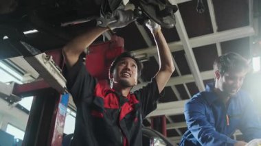İki erkek tamirci işbirliği yapıyor, Latin ve Asyalı işçiler otomotiv tekerleklerini tamir ediyor ve garaj istasyonunda araba süspansiyonlarını koruyor, ve araç taşımacılığı sektöründe teknisyen mühendisliği hizmeti veriyor..