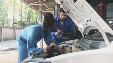 EV araba kontrolü, tamirci iş arkadaşı sabit otomobil garaj istasyonunda elektrik motoru ve pil hizmetini denetliyor ve koruyor, profesyonel teknoloji ulaşım sektörü.