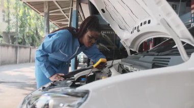 EV araba kontrolü, siyah kadın tamirci sabit otomobil garaj istasyonunda elektrik motoru ve pil hizmetini denetliyor ve koruyor, profesyonel teknoloji taşımacılığı sektörü.