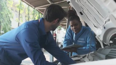 EV araba kontrolü, tamirci iş arkadaşı sabit otomobil garaj istasyonunda elektrik motoru ve pil hizmetini denetliyor ve koruyor, profesyonel teknoloji ulaşım sektörü.