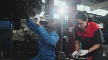 İki kadın tamirci tartışıyor, Latin ve Siyah işçiler otomotiv tekerleklerini tamir ediyor ve garaj istasyonunda araba süspansiyonlarını koruyor, ve araç taşımacılığı sektöründe teknisyen mühendisliği hizmeti veriyor.