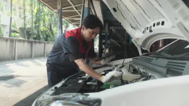 EV araba kontrolü, Asyalı erkek tamirci sabit otomobil garaj istasyonunda elektrik motoru ve pil hizmetini denetliyor ve koruyor, profesyonel teknoloji ulaşım sektörü.