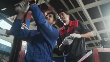 İki erkek tamirci işbirliği yapıyor, Latin ve Asyalı işçiler otomotiv tekerleklerini tamir ediyor ve garaj istasyonunda araba süspansiyonlarını koruyor, ve araç taşımacılığı sektöründe teknisyen mühendisliği hizmeti veriyor..