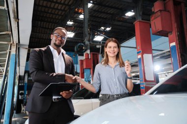 Garanti araçları servis işi, beyaz kadın müşteri araba anahtarını siyah erkek sigorta acentesinden alarak mutlu, tadilat bittikten sonra otomotiv garajı istasyonunda tamir ve bakım..