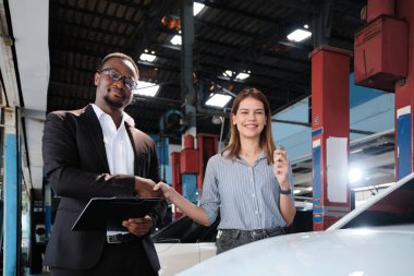 Garanti araçları servis işi, beyaz kadın müşteri araba anahtarını siyah erkek sigorta acentesinden alarak mutlu, tadilat bittikten sonra otomotiv garajı istasyonunda tamir ve bakım..