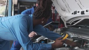 EV araba kontrolü, tamirci iş arkadaşı sabit otomobil garaj istasyonunda elektrik motoru ve pil hizmetini denetliyor ve koruyor, profesyonel teknoloji ulaşım sektörü.