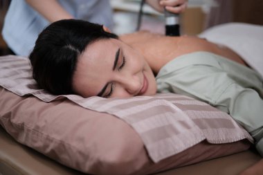 Bedensel kas doktorları tarafından sırt ağrısı için jel ultrasonu cihazı ile tedavi edilen Latin bir kadın hasta, kaplıca kliniğinde pasif tıbbi terapi ve sağlık hizmetleri masajı..