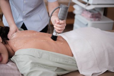 Yakın çekim, İspanyol kadın hasta iyileşme sürecinde, sırt ağrısı için fiziksel kas terapisti jel ultrasonu, kaplıca kliniğinde pasif tıbbi terapi ve sağlık hizmetleri masajı..