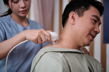Yakın çekim, Asyalı erkek hasta iyileşme sürecinde, kadın kas doktoru tarafından jel ultrasonu, omuz ağrısı, kaplıca kliniğinde pasif tıbbi terapi ve sağlık hizmetleri masajı..