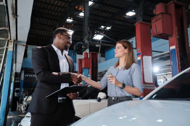 Garanti araçları servis işi, beyaz kadın müşteri araba anahtarını siyah erkek sigorta acentesinden alarak mutlu, tadilat bittikten sonra otomotiv garajı istasyonunda tamir ve bakım..