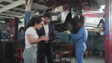 Kadın müşteri ve Latin erkek müdür, Siyah Mekanik Kadın, araba süspansiyonu ve sigortalı garantisi, otomotiv garajında müşteri hizmetleri bakımı ve ulaşım endüstrisi konularını görüştü..