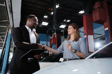 Garanti araçları servis işi, beyaz kadın müşteri araba anahtarını siyah erkek sigorta acentesinden alarak mutlu, tadilat bittikten sonra otomotiv garajı istasyonunda tamir ve bakım..