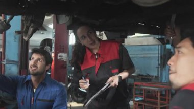 Profesyonel işçi ekipleri, çok ırklı mühendisler ve makine işçileri, garaj istasyonunda birlikte araba süspansiyonlarını tamir etmek ve sürdürmek ve otomotiv sektöründe hizmet işleri yapmak için işbirliği yapıyorlar..