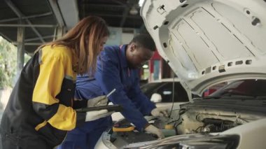 EV araba kontrolü, tamirci iş arkadaşı sabit otomobil garaj istasyonunda elektrik motoru ve pil hizmetini denetliyor ve koruyor, profesyonel teknoloji ulaşım sektörü.