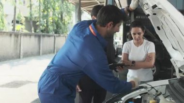 Kadın müşteri ve Asyalı erkek müdür, EV otomobil tamirhanesinde teknisyen motor tamirciliği, akü tamirciliği, müşteri hizmetleri bakımı ve ulaşım sektörü konularında görüştü..