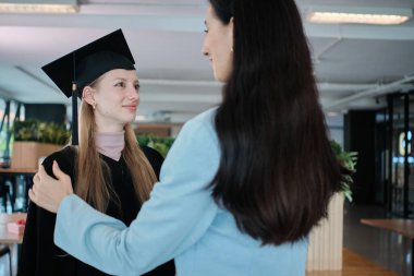 Beyaz anne, genç kızın mezuniyet elbisesini diploma başarı seremonisi, akademik üniversite kampüsünde diploma başarısı, mutlu tebrik ve neşeli aile kilometre taşı ile düzenliyor..