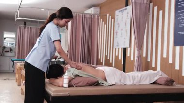 Asyalı erkek hasta kas gevşemesi için fizyoterapistin elinden alınan kas gevşemesi, kaplıca kliniğinde pasif oryantal tıbbi tedavi ve sağlık hizmetleri yaşam tarzı nedeniyle masaj yaptırıyor..