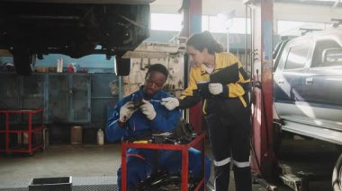 Latin kadın müfettiş araba süspansiyonlarının hizmet listesi üzerinde çalışıyor. Tamir garajında tamirci, otomobil ve ulaşım sektöründe profesyonel mühendis işleriyle uğraşıyor..
