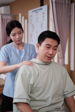 Asyalı olgun erkek hasta omuz masajı, kas germe ve ağrı kesici için iyileşme. Fizyoterapist doktor eliyle iyileşmiş. Sağlık merkezindeki pasif tıbbi tedavi..