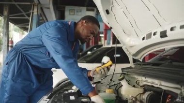 EV araba kontrolü, siyah erkek tamirci sabit otomobil garaj istasyonunda elektrik motoru ve pil hizmetini denetliyor ve koruyor, profesyonel teknoloji taşımacılığı sektörü.