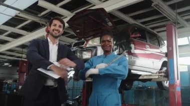 Profesyonel ortağın portresi, Latin erkek müdür ve siyah kadın tamirci gülümsemesi, kollarını kavuşturmuş, neşeli, hizmet talep işi, garaj otomobil tamirhanesinde araba tamiri ve bakım..