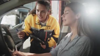 Latin kadın tamirci beyaz müşterili kadına EV araç iç konsol tamir talebi ve araba garantisi, otomotiv garajında müşteri hizmetleri bakımı, ulaşım endüstrisi hakkında açıklama yapıyor..