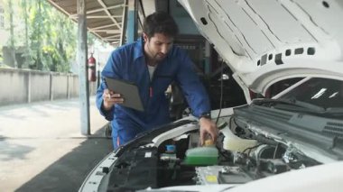EV araba kontrolü, İspanyol erkek tamirci sabit otomobil garaj istasyonunda elektrik motoru ve pil hizmetini denetliyor ve sürdürüyor, profesyonel teknoloji taşımacılığı sektörü.