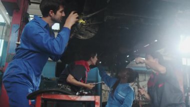 Profesyonel işçi ekipleri, çok ırklı mühendisler ve makine işçileri, garaj istasyonunda birlikte araba süspansiyonlarını tamir etmek ve sürdürmek ve otomotiv sektöründe hizmet işleri yapmak için işbirliği yapıyorlar..