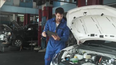 EV araba kontrolü, İspanyol erkek tamirci sabit otomobil garaj istasyonunda elektrik motoru ve pil hizmetini denetliyor ve sürdürüyor, profesyonel teknoloji taşımacılığı sektörü.