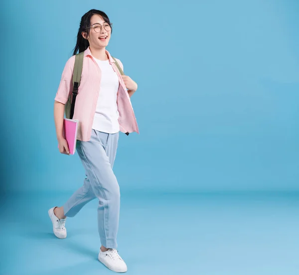 Young Asian student on blue background